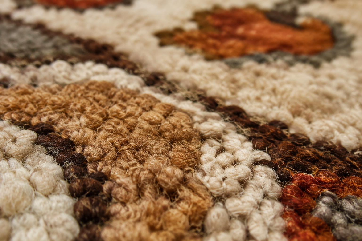 Close-up macro shot of a handmade wool rug showing the natural fibers and textur…